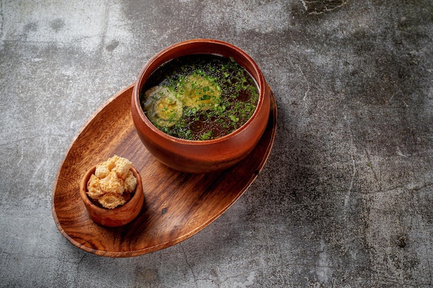 Kippensoep met gekookt ei besprenkeld met dille en peterselie greens in een houten kom met broodkruimels staat geïsoleerd op een stenen tafel, Flatlay