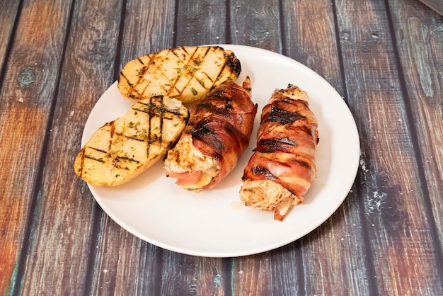 Kiprolletjes gevuld met kaas en ham omwikkeld met gebakken spekjes gegarneerd met geroosterde aardappelen met knoflook- en peterseliesaus