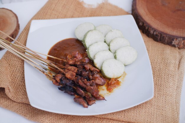 kipsaté op een wit bord met pindasaus