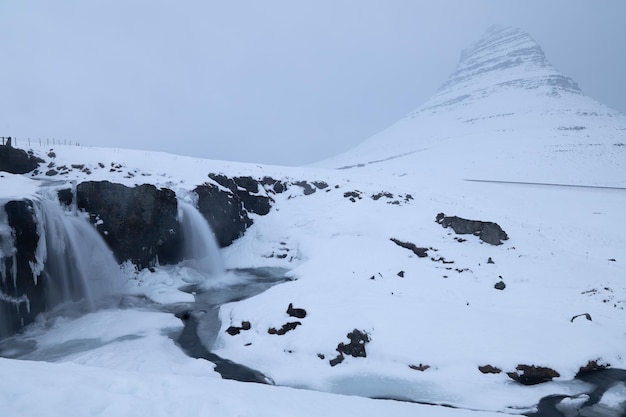 Kirkjufell Mountain and two waterfalls under the snow in Snaefellsnes Peninsula Iceland