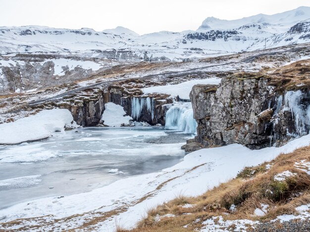 Kirkjufellfoss waterfall with its surrounding view water freeze the most popular landmark in Iceland