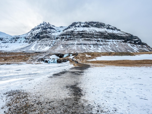 周囲の景色を望むKirkjufellfoss滝は、アイスランドで最も人気のあるランドマークを凍らせます