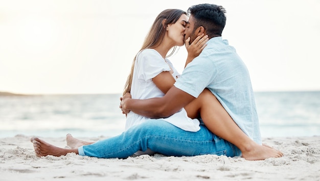 Kiss beach and love of couple on a date for anniversary valentines day or romance summer holiday with clear sky ocean waves and sand Romantic intimate and marriage honeymoon or engagement people