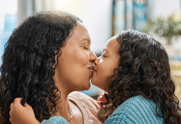 Kisses are always free Shot of an adorable little girl giving her mother kiss while bonding with her in the living room at home