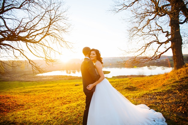Поцелуи жениха и невесты в день их свадьбы возле осеннего дерева