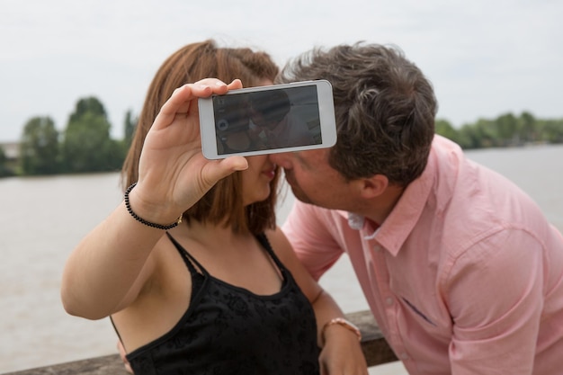 Photo kissing couple, making a selfie on vacation at summer