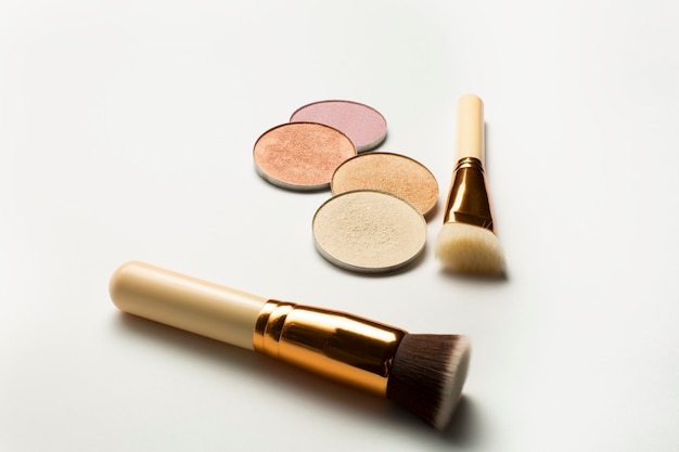 Kit of highlighters with cosmetic brushes over a white background