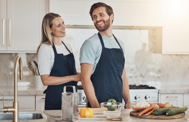 Kitchen apron and couple with cooking smile and healthy food with ingredients bonding and anniversary Happy people home and man with woman recipe and bonding with activity lunch and vegetables