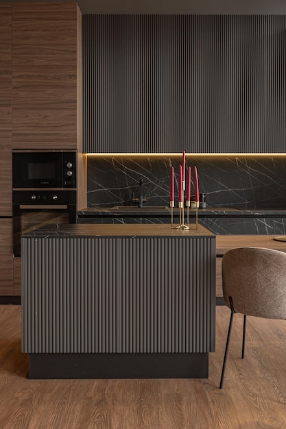 Kitchen area in a chic expensive interior of a luxury home with a dark black and brown modern design with wood trim and led light