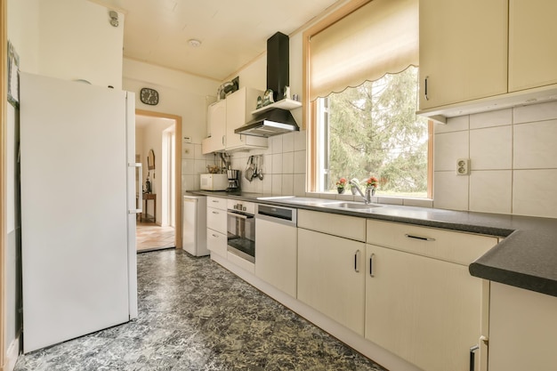 A kitchen area with white cabinets and black counter tops on the floor in front of the refrigerator door is open