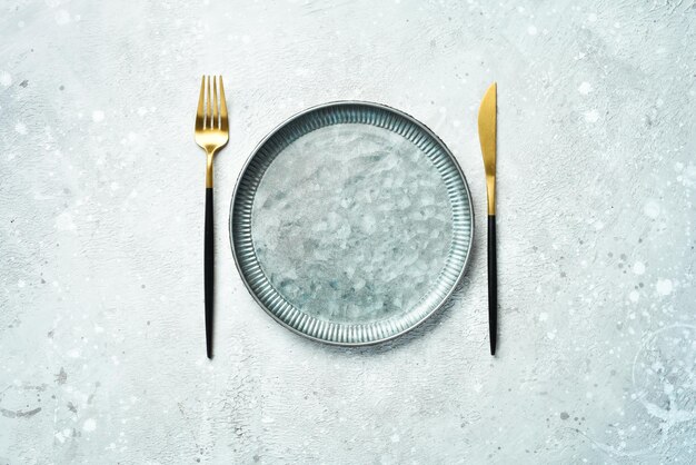 Photo kitchen background metal plate and cutlery on a gray stone background top view