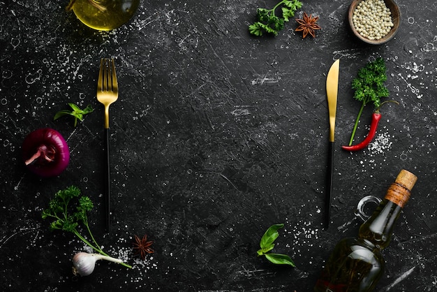 Kitchen banner Spices vegetables and cutlery on a black stone background Top view Free space for text