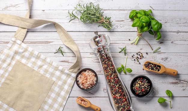 Photo kitchen beige apron wooden spoon with spices pepper mill wood kitchen utensils on a wooden background top view