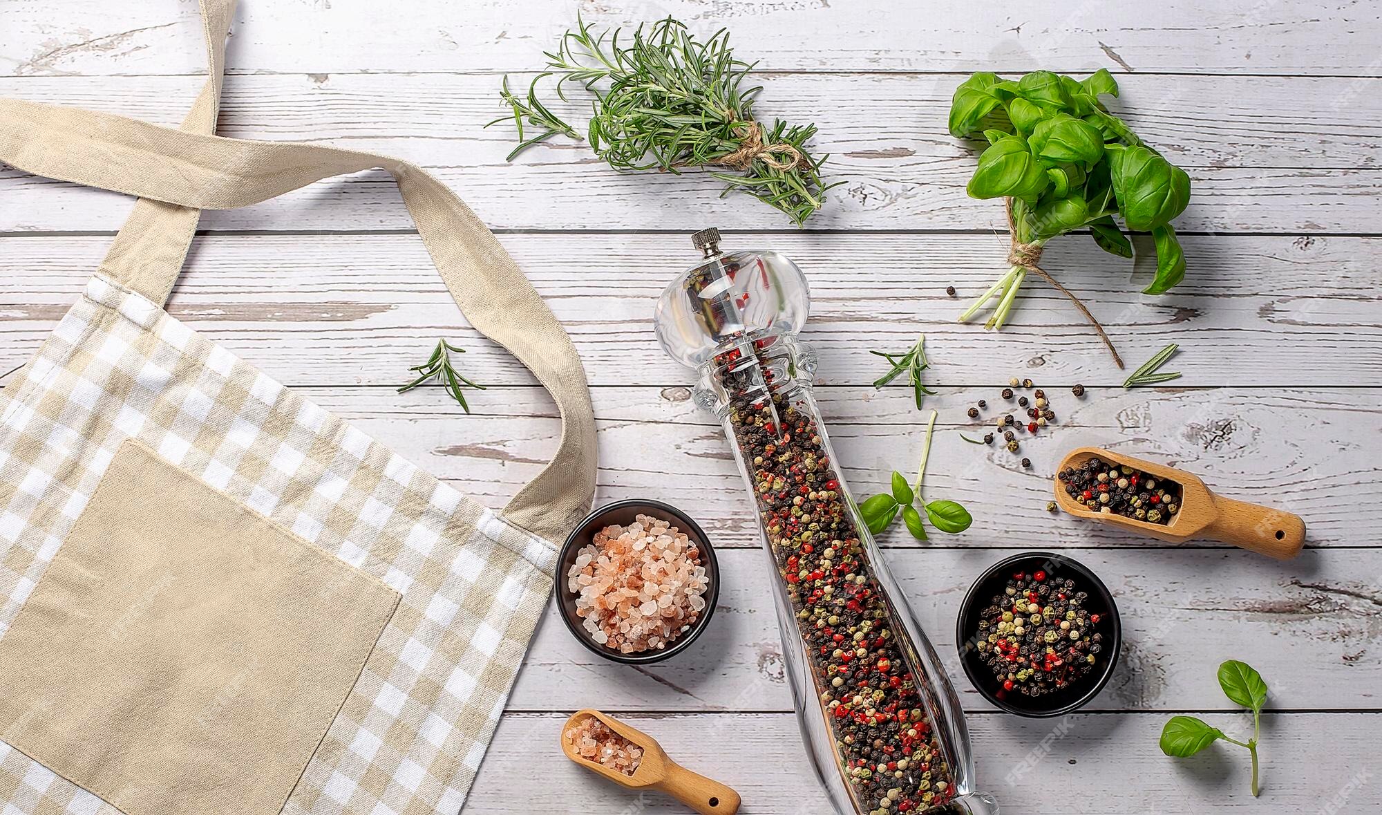 Premium Photo  Kitchen beige apron wooden spoon with spices pepper mill  wood kitchen utensils on a wooden background top view