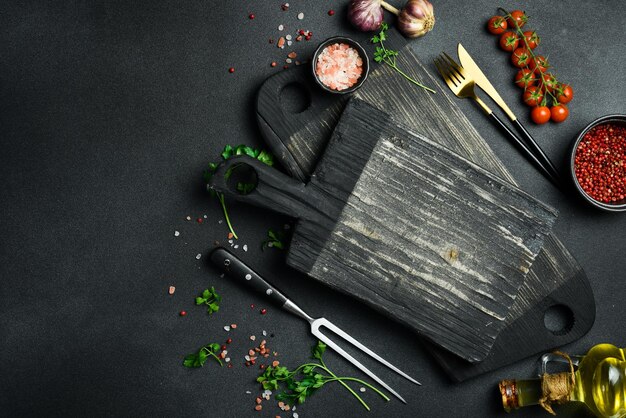 Kitchen board and kitchen wooden utensils on the kitchen table On a dark background Top view Free space for text