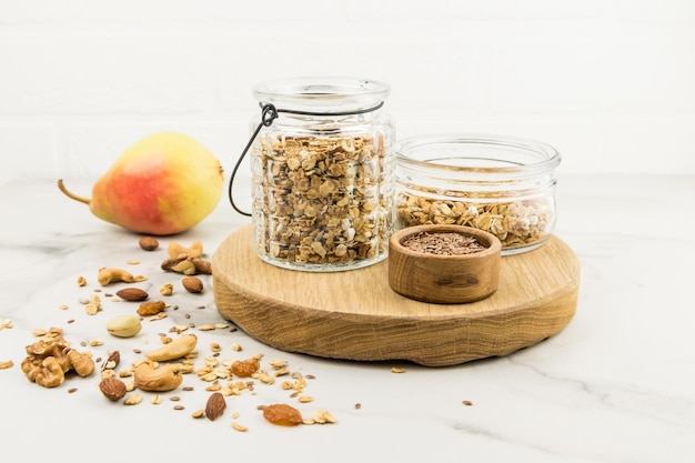 Kitchen board with glass jars filled with muesli or granola for making avtraka. nuts, ripe pear to improve the taste. healthy eating.