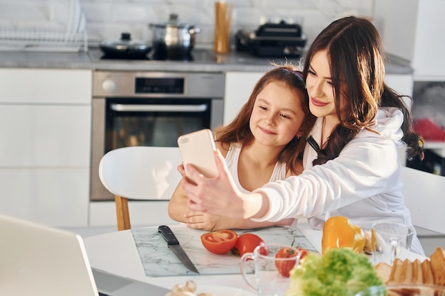 On the kitchen Caucasian young mother with her daughter is at home together