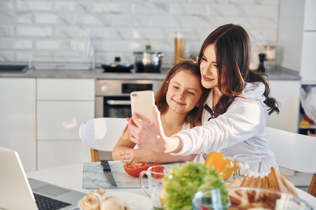 On the kitchen Caucasian young mother with her daughter is at home together