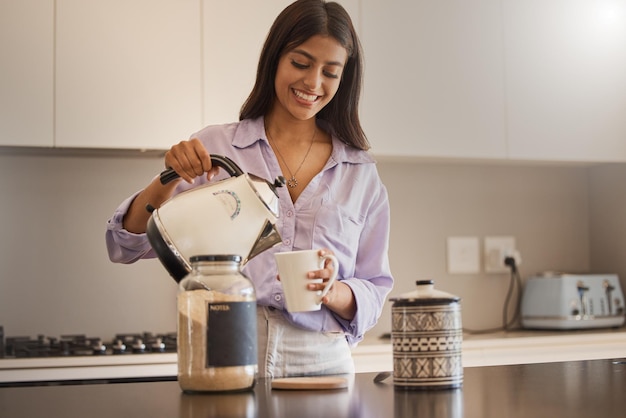 kitchen coffee and morning with a woman pouring a drink or fresh beverage in her home for caffeine kettle water and tea with a happy young female making a mug or cup for drinking in her house