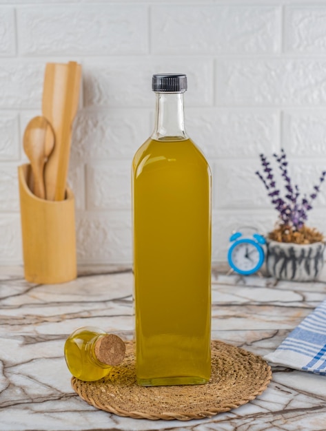 Foto concetto di cucina e bottiglia di vetro riempita di olio. bottiglia di olio d'oliva su sfondo di marmo.