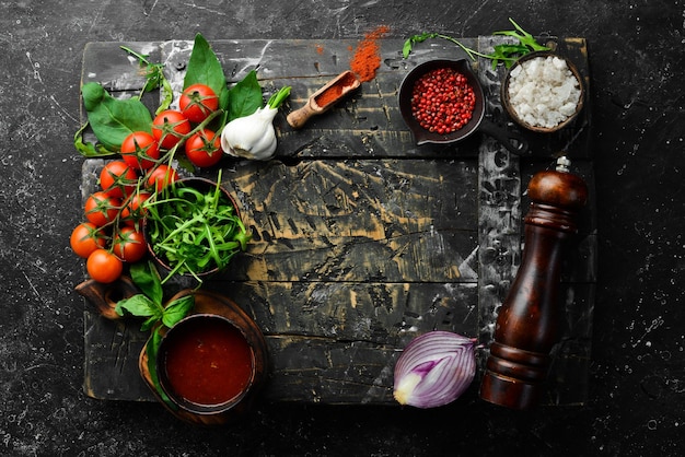 Kitchen cooking background cherry tomatoes onions spices and herbs On a black background