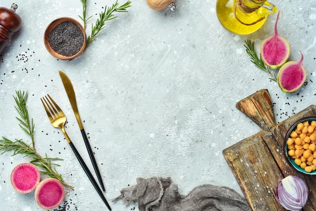 Kitchen cooking background: kitchen board, cutlery, vegetables and spices. Top view. On a stone background.