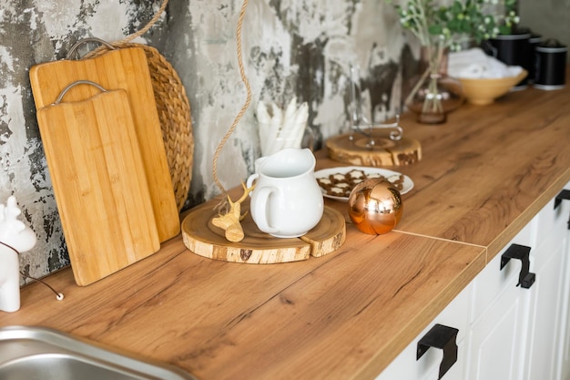 Kitchen cooking utensils in ceramic storage pot and Christmas decor on a shelf on a rustic wooden wall.