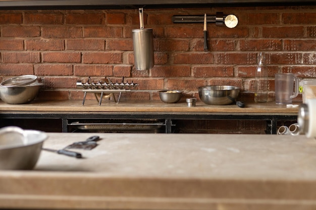 kitchen countertop with metal cookware and tools arranged neatly against a brick wall