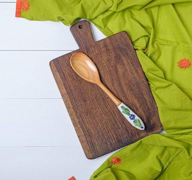 Kitchen cutting board and wooden spoon on white table