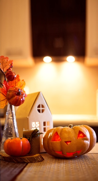 사진 할로윈과 가을을 위한 주방 장식 - 빛나는 판지 집, 양초, 단풍이 있는 꽃다발, 감, 잭오랜턴.