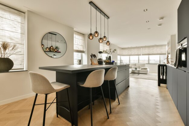 Una cucina e una sala da pranzo in un appartamento moderno con pavimenti in legno, pareti bianche e armadietti neri