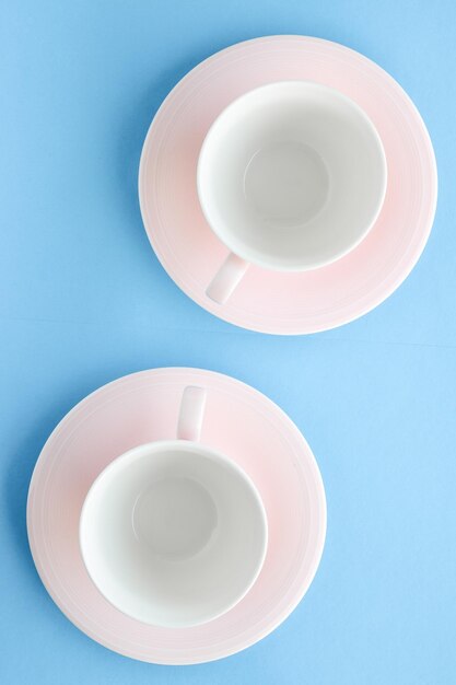 Kitchen dishware and drinks concept - empty cup and saucer on blue background flatlay