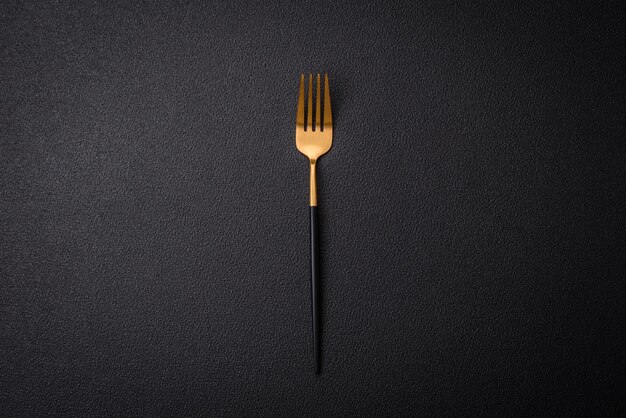 Kitchen fork made of steel on a dark textured background