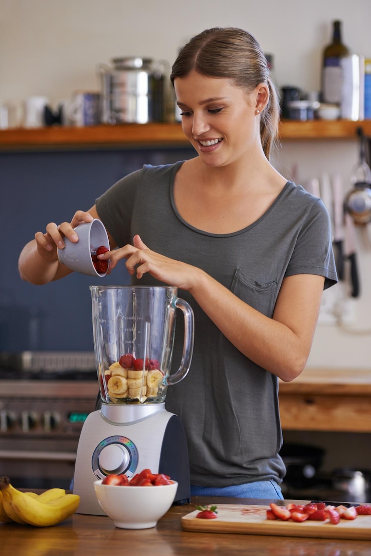 Photo kitchen happy woman and blender for fruit smoothie nutrition or food for healthy diet at table in home person smile and mixer for drink juice or strawberry for wellness with organic beverage