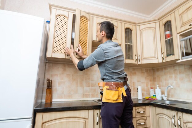 kitchen installation. Worker assembling furniture.