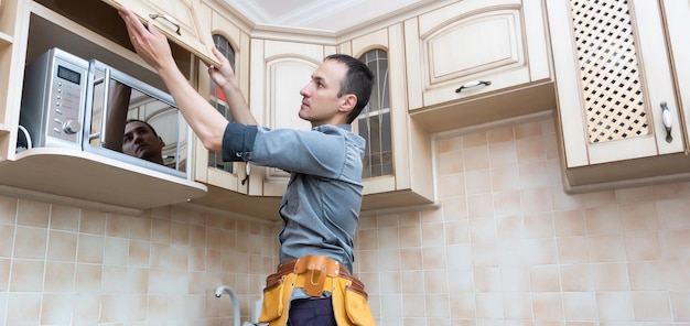 kitchen installation. Worker assembling furniture.