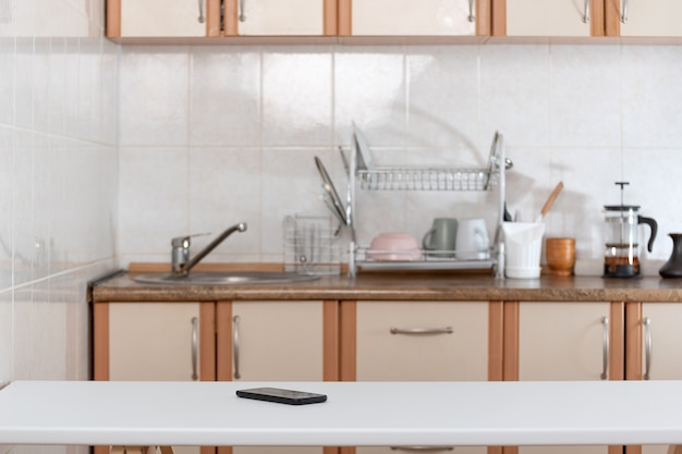 Kitchen interior and mobile phone on table. Forgotten smartphone.