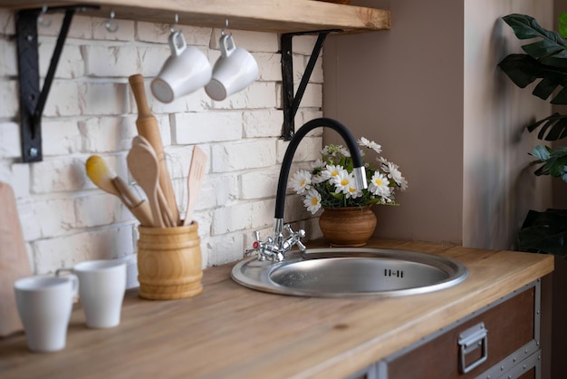 The kitchen interior. There are dishes, flowers, a sink on the table.