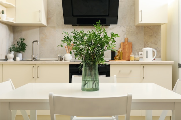 Kitchen interior with wooden table with vase with plant