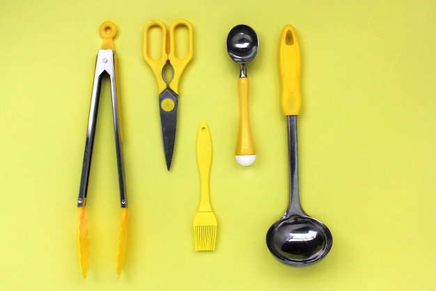 Accessori per mestoli da cucina, forbici, pinze, pennello, cucchiaio da gelato giallo su sfondo giallo