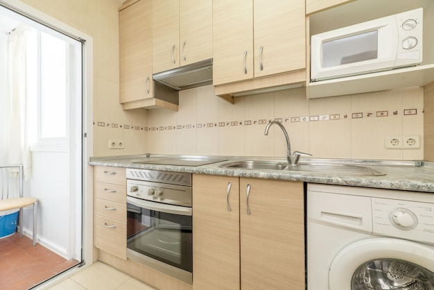 Kitchen of minimalist design with smooth white wood furniture and combined floors of porcelain and light flooring