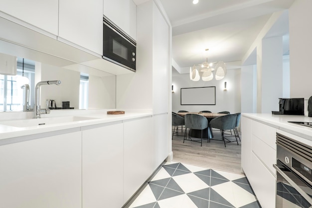 Kitchen of minimalist design with smooth white wood furniture and combined floors of porcelain and light flooring