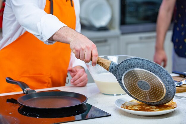 Kitchen Preparation the chef in a bright apron fries fresh pancakes in two pans