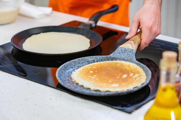 Kitchen Preparation: the chef fries fresh pancakes in two pans