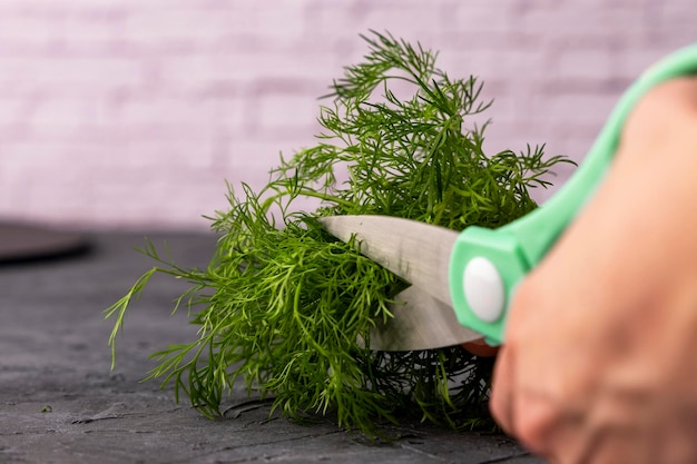 Kitchen scissors cutting dill in the kitchen on a cutting board