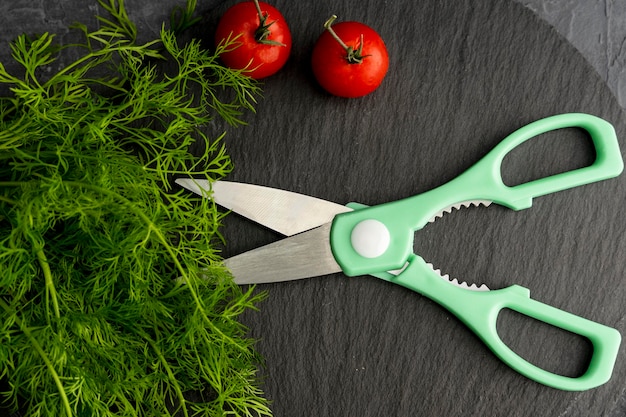 Kitchen scissors cutting dill in the kitchen on a cutting board