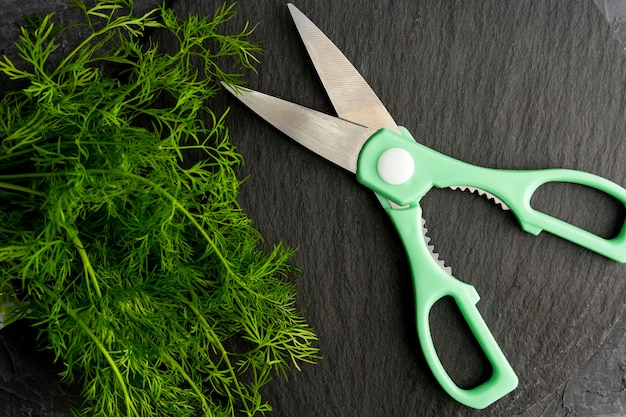 Kitchen scissors cutting dill in the kitchen on a cutting board