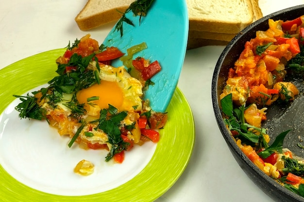 La spatola da cucina aggiunge shakshuka di uova fritte in salsa di verdure al piatto. cucina ebraica e araba.