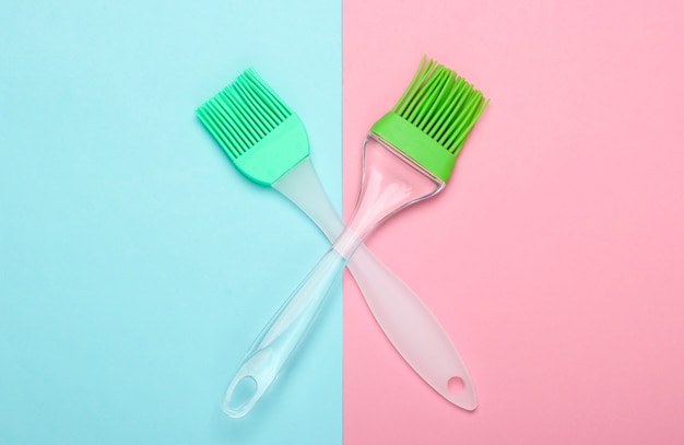 Kitchen spatula and brush on pink blue pastel background. Top view