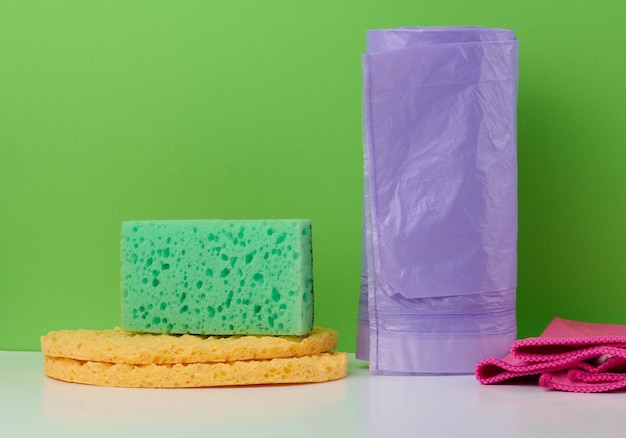 Photo kitchen sponge rag and plastic bag roll on green background